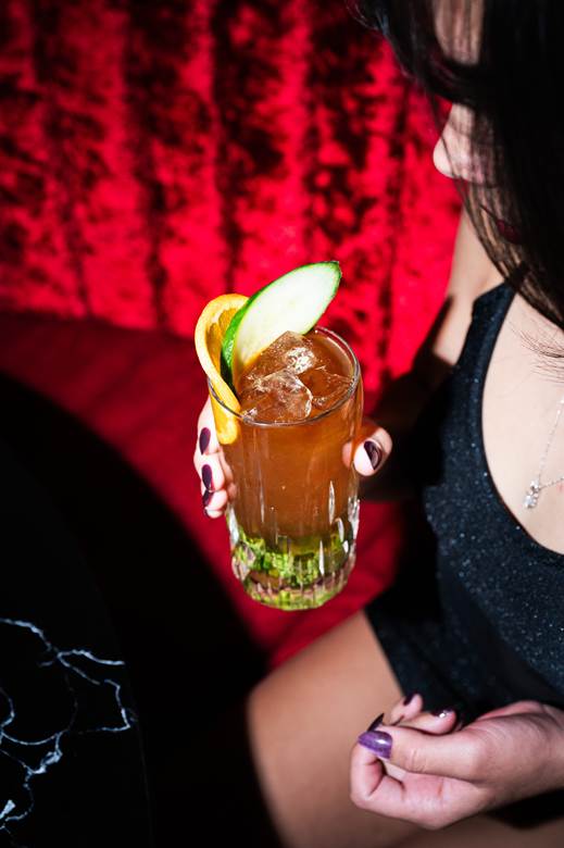 A woman holding a drink during Happy Hour at ZuZu in Detroit.